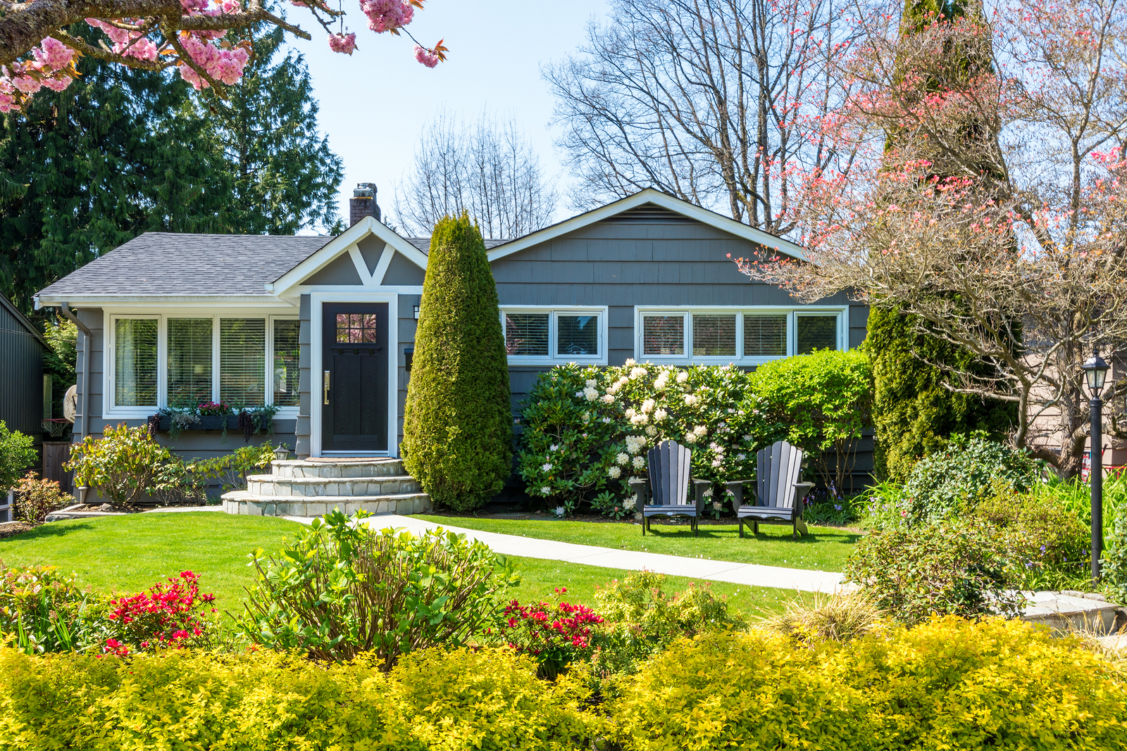 Cozy house with beautiful landscaping on a sunny day. Home exterior.